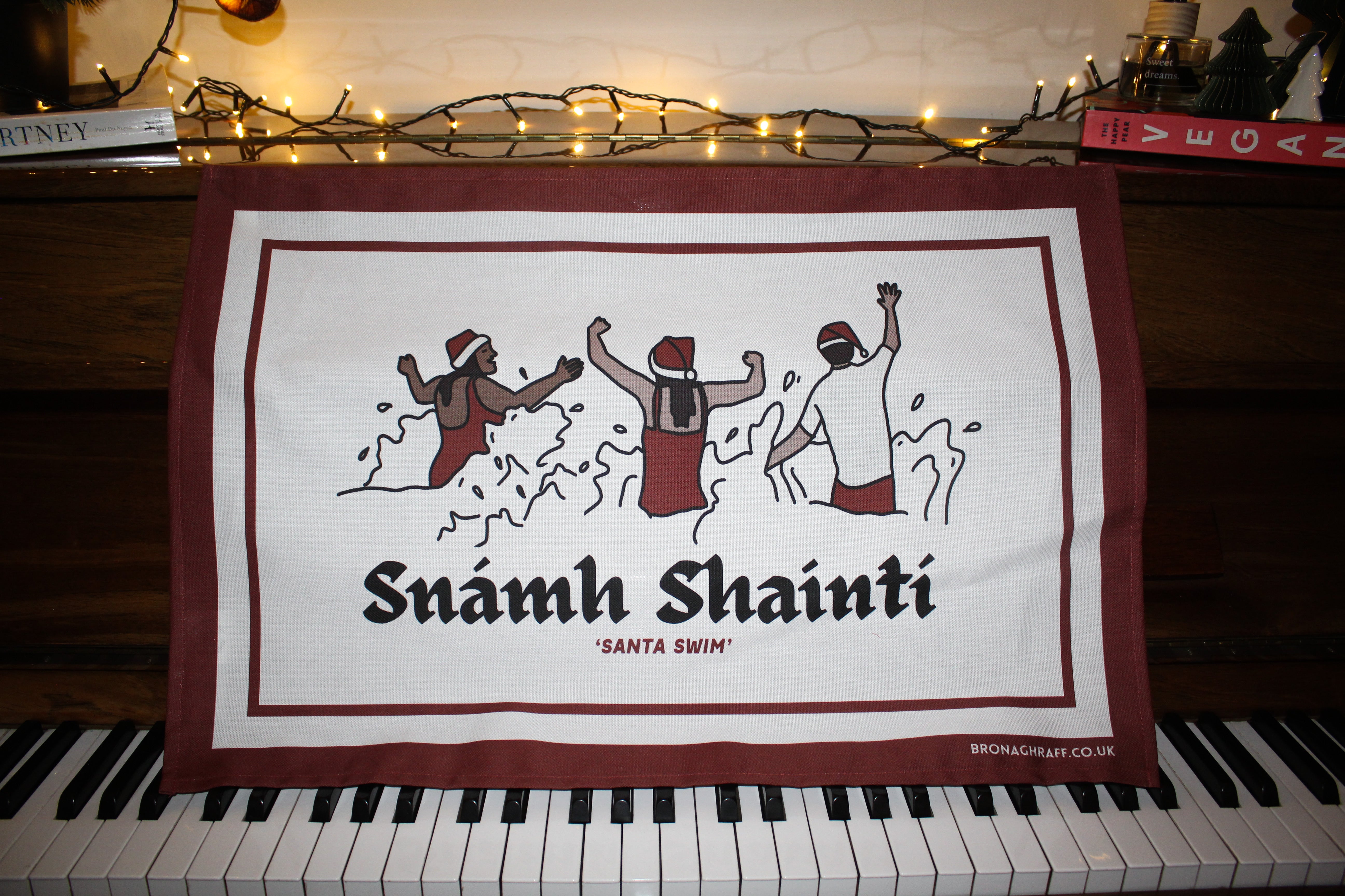 Festive tea towel featuring joyful swimmers in the sea, celebrating the beloved Irish tradition of the Christmas Day swim.