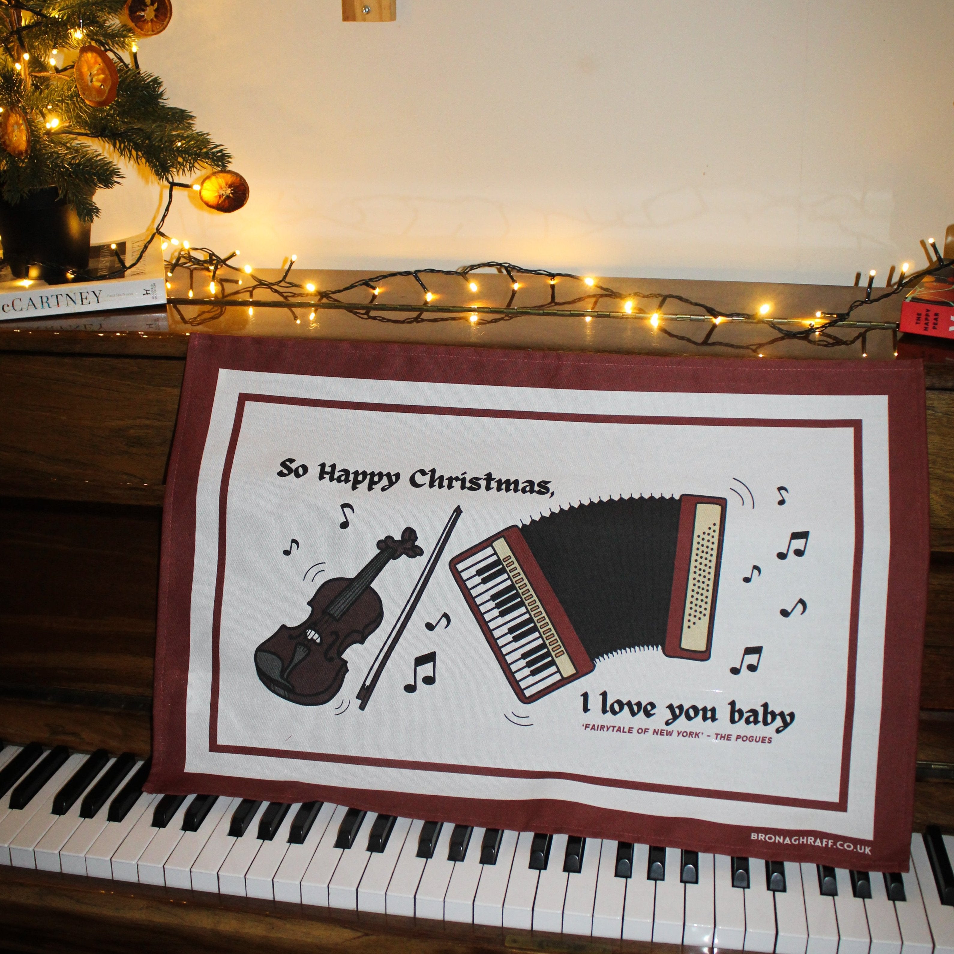 Eco-friendly Christmas tea towel with traditional Irish music elements, featuring a fiddle and accordion alongside nostalgic lyrics