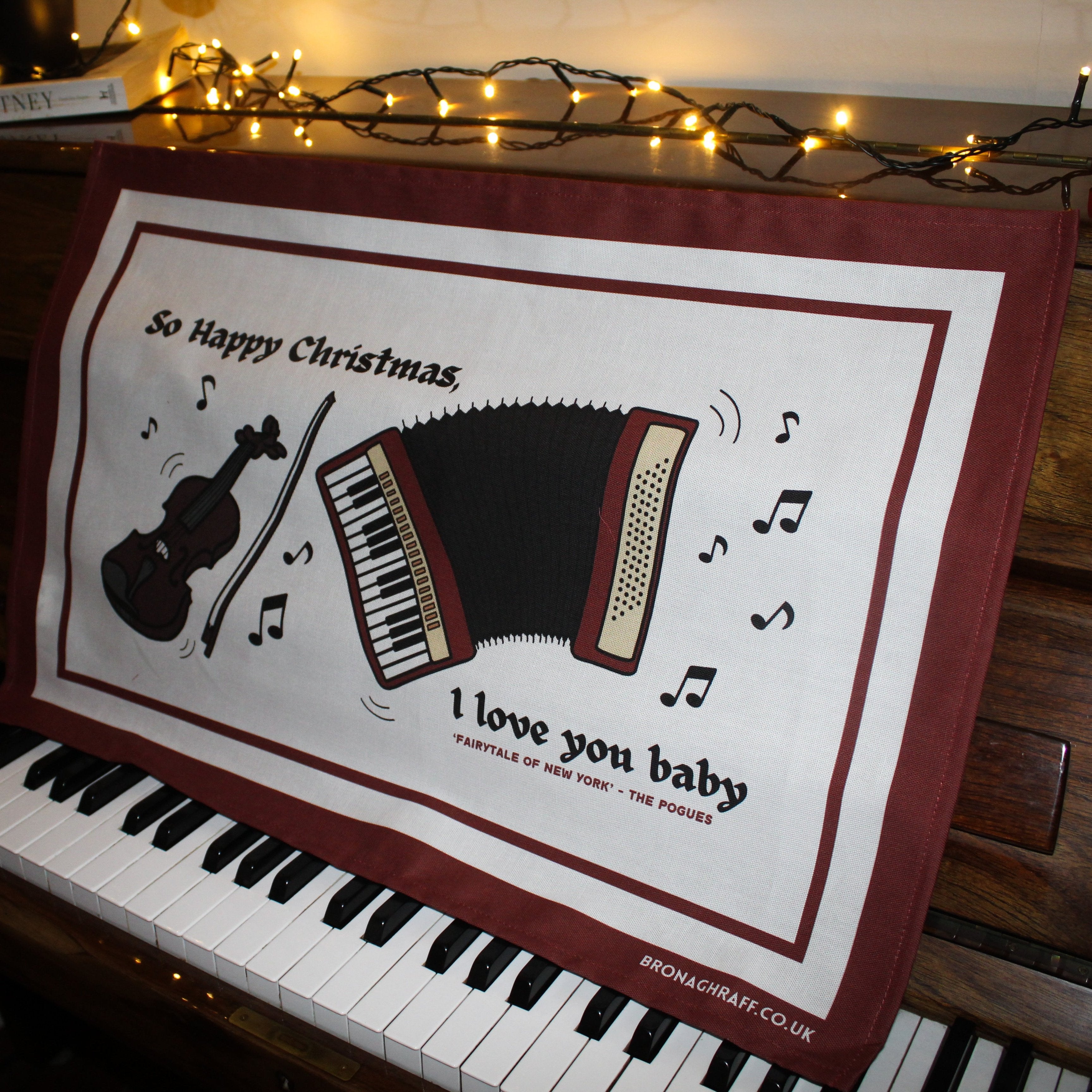 A nostalgic Irish tea towel blending music and Christmas, with a fiddle, accordion, and lyrics from a beloved holiday song