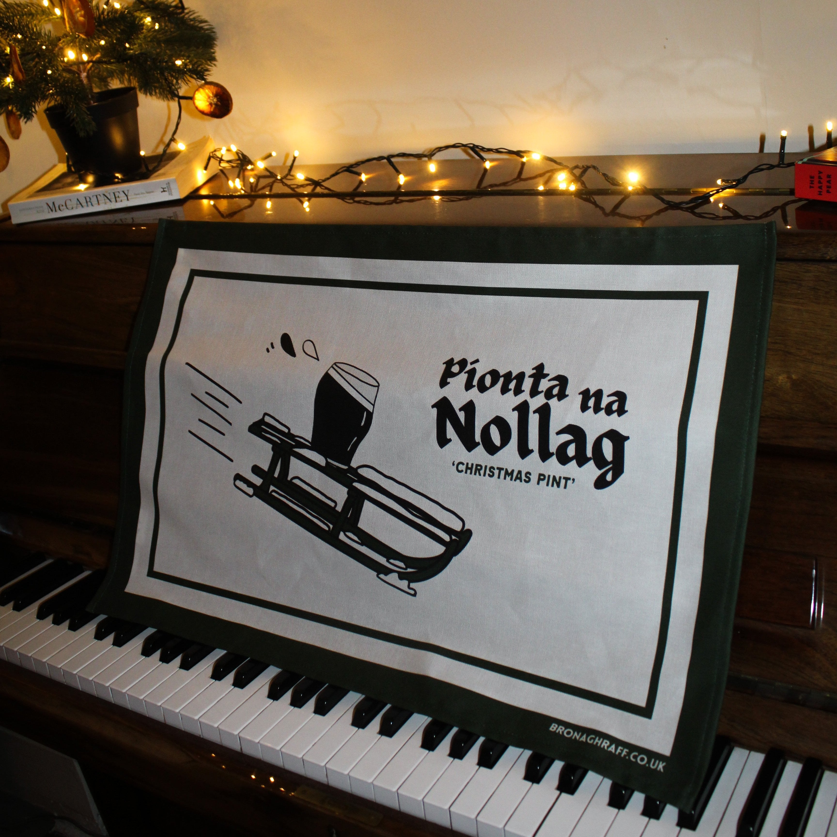 Hand-drawn tea towel with a humorous Irish design of a pint on a sleigh, celebrating Christmas and Irish traditions