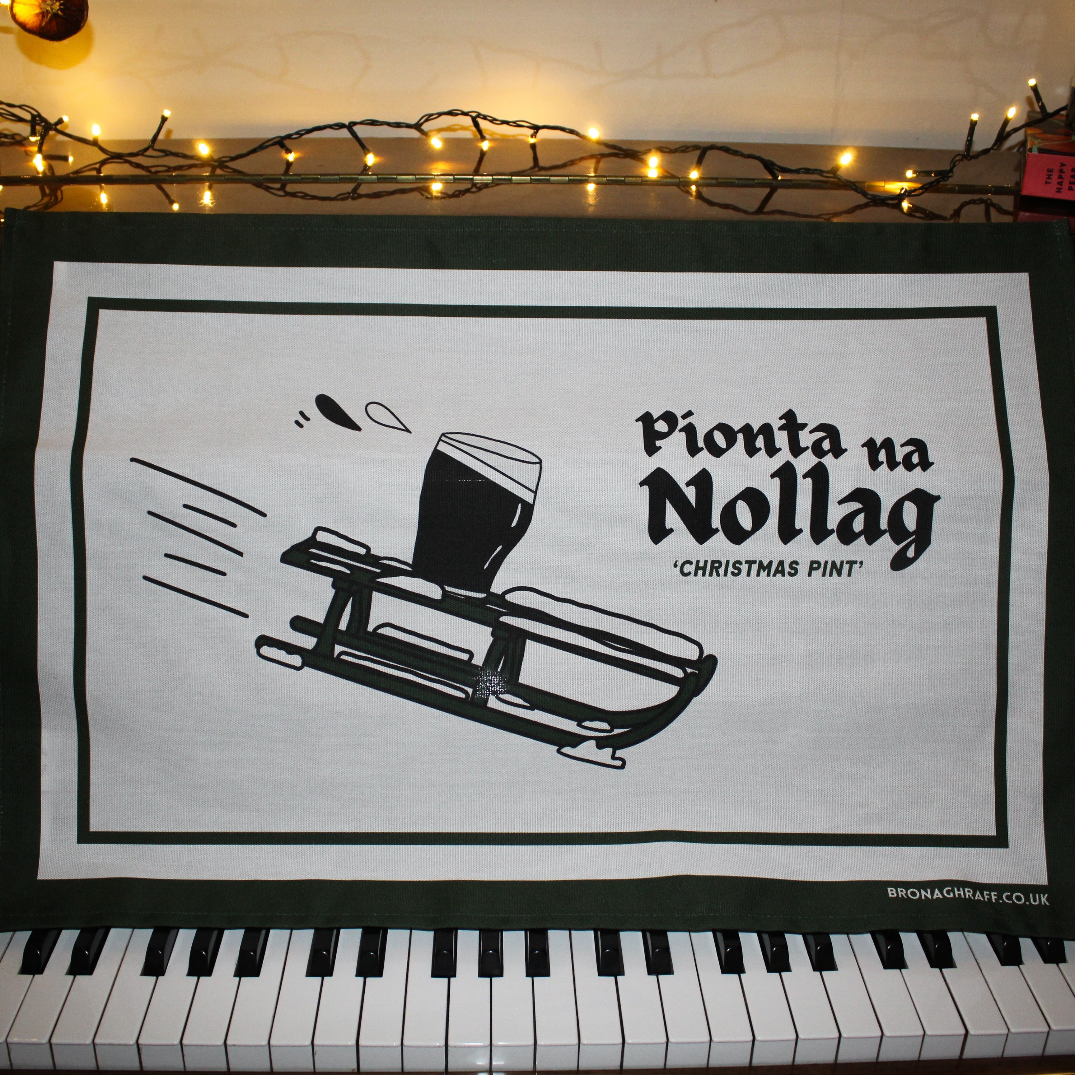 Eco-friendly tea towel with a fun Irish design showing a pint of Guinness on a sleigh and the phrase 'Christmas Pint' in Irish