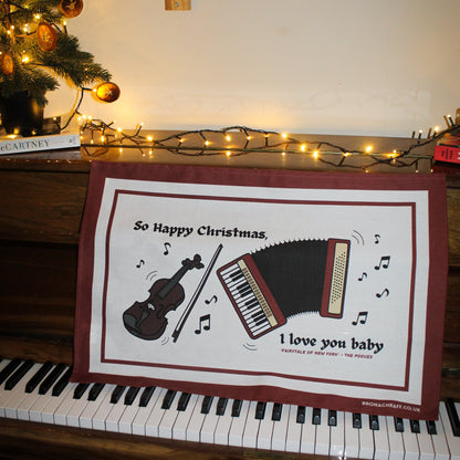 Eco-friendly Christmas tea towel with traditional Irish music elements, featuring a fiddle and accordion alongside nostalgic lyrics